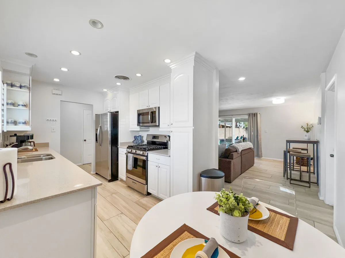 A bright and modern kitchen scene featuring sleek appliances, a breakfast table setup, and an open layout. The space feels ready for cooking, casual conversation, or family gatherings, with a welcoming mood that invites guests to linger.