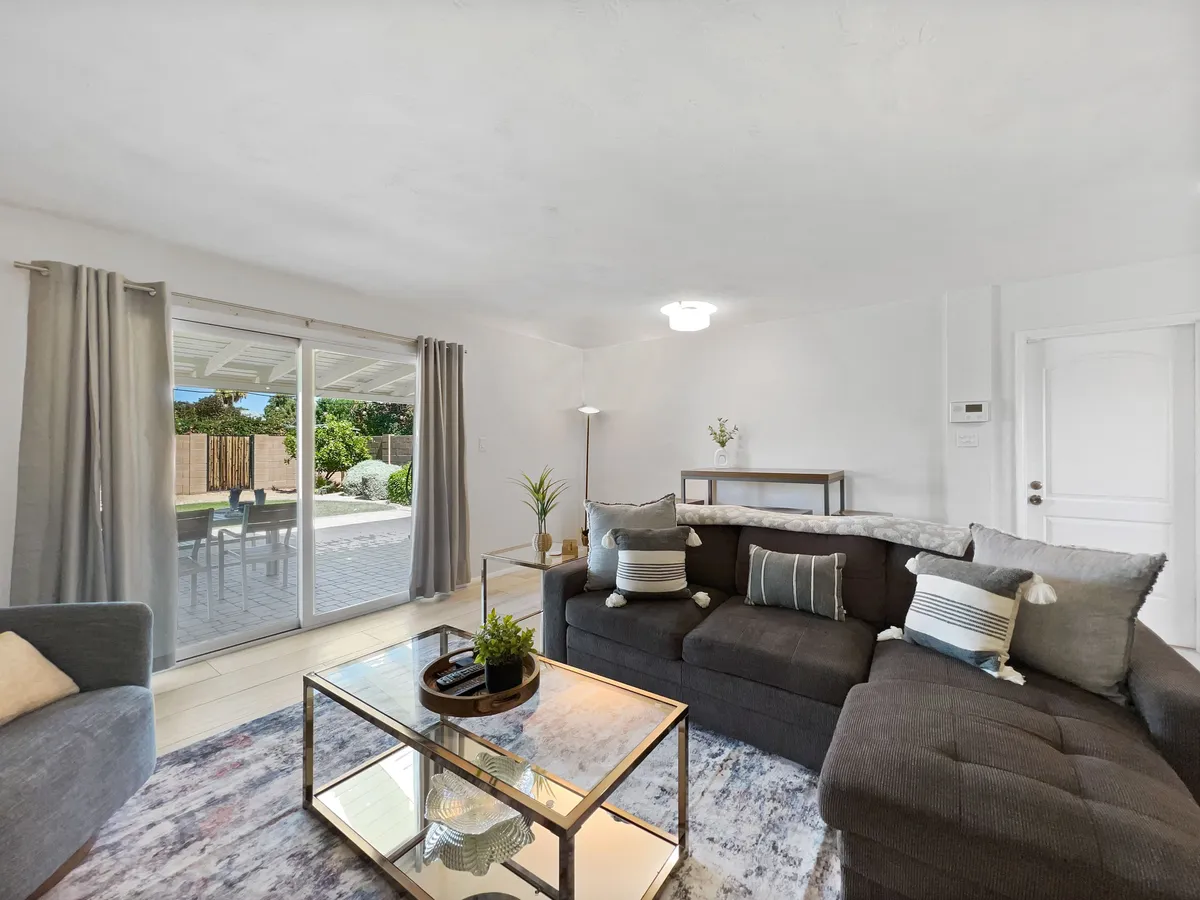 A comfortable living room with a sofa and coffee table bathed in sunlight from a window, creating a relaxed, inviting mood. The space is perfect for socializing, reading, or simply enjoying a quiet moment.