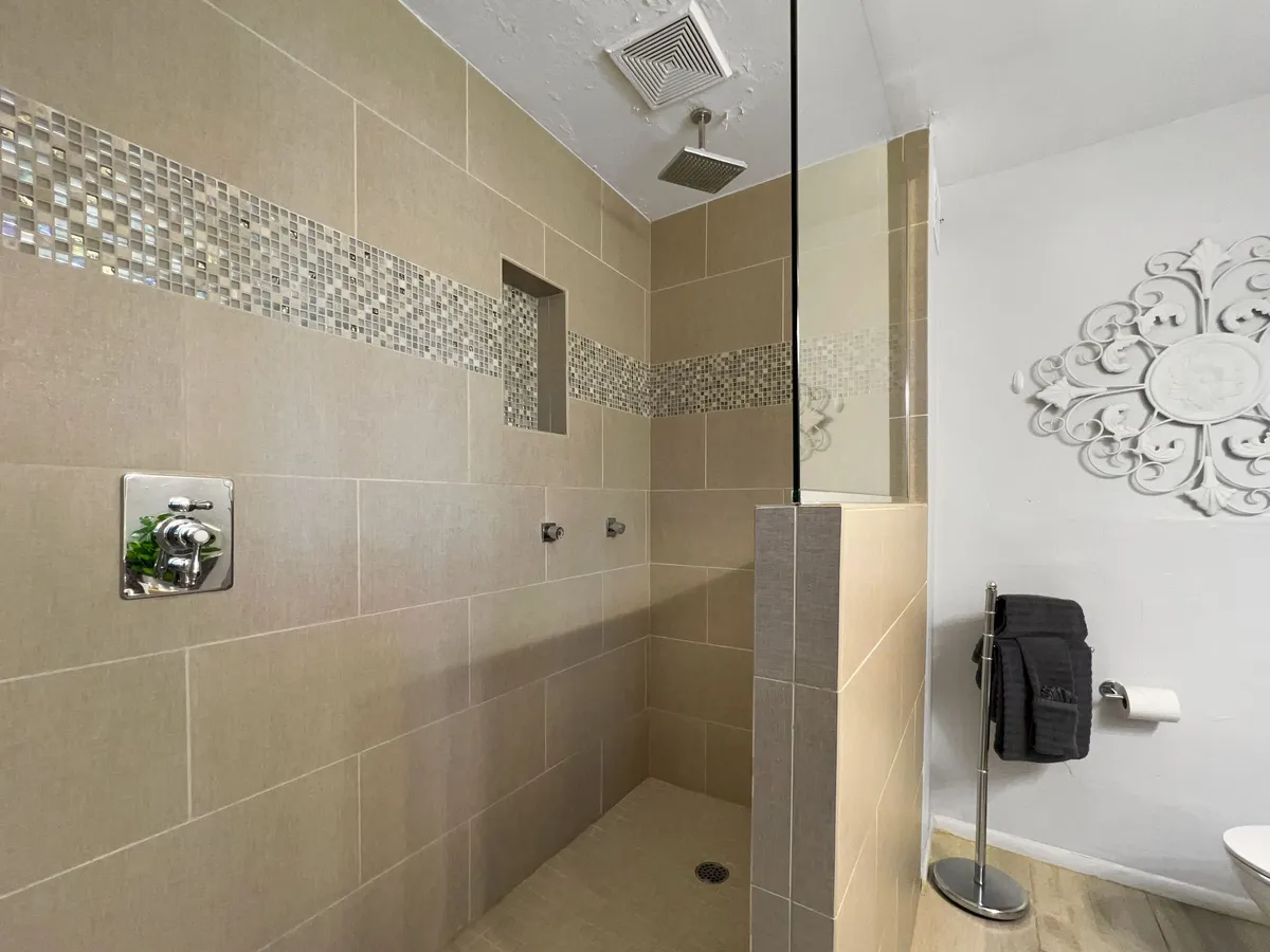 A tranquil bathroom scene featuring a glass-enclosed walk-in shower with decorative tile and a modern showerhead, evoking spa-like relaxation.