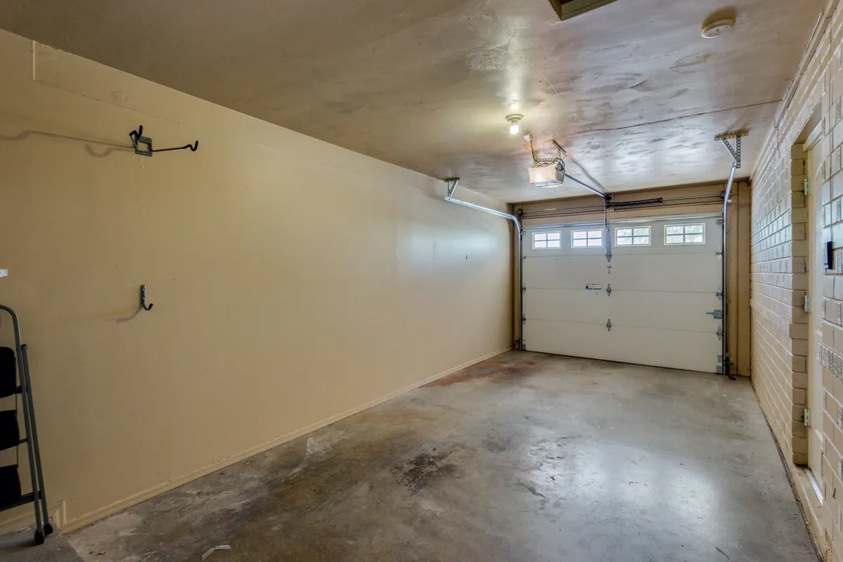 This image shows a private garage with a visible garage door, bare walls, and a concrete floor. The space is practical and uncluttered, designed for parking vehicles, storing tools, or organizing equipment.
