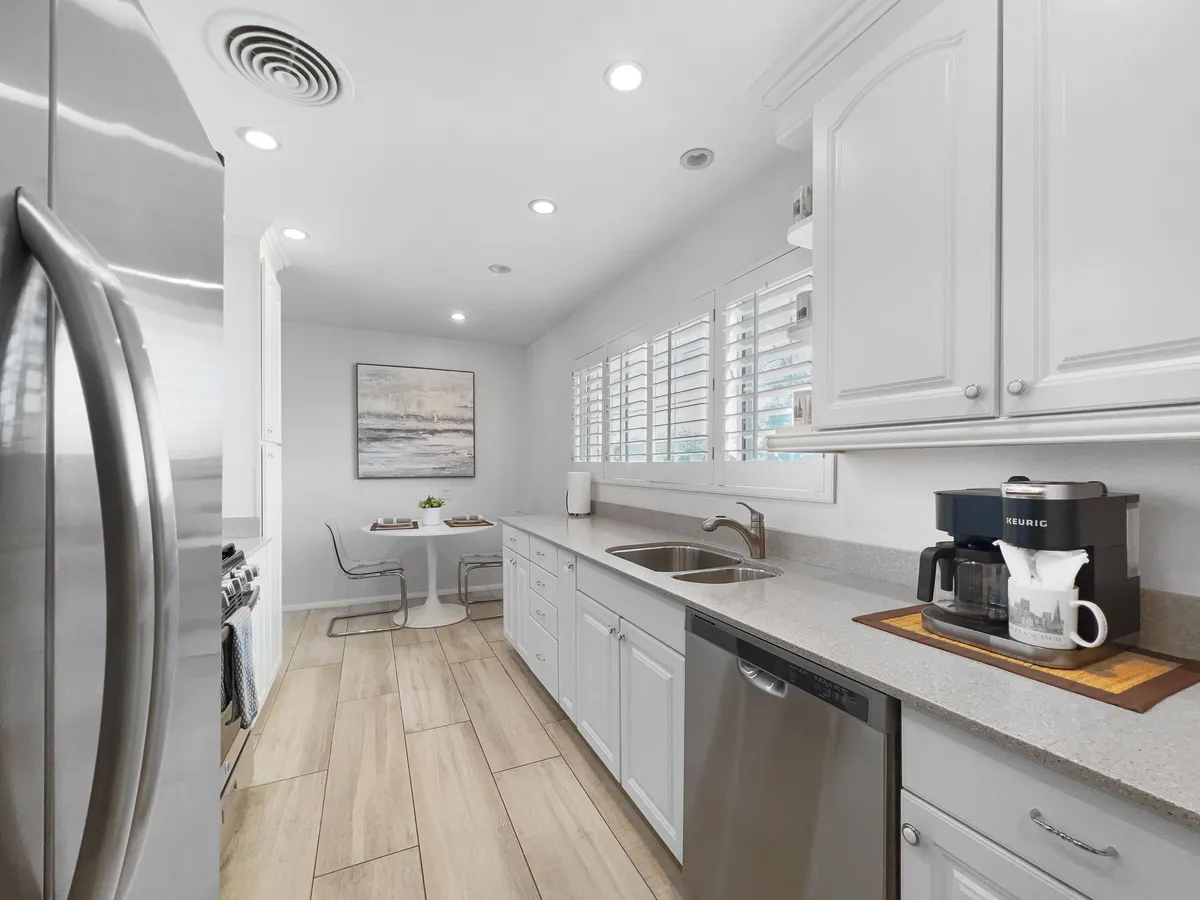 A cozy kitchen nook with a modern coffee machine, stainless steel refrigerator, and a small dining table set for casual meals. Sunlight streams in, inviting residents to unwind over breakfast or coffee before heading out to explore.